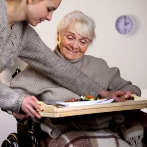 une jeune femme donnant un repas à une femme en fauteuil roulant