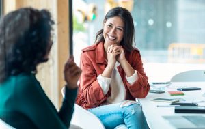 femme discutant avec une autre femme, en souriant