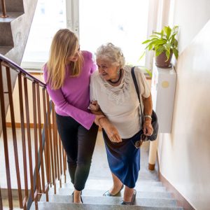 Une femme aidant une personne âgée à monter des escaliers