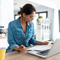 Femme lisant un contrat, devant un ordinateur portable