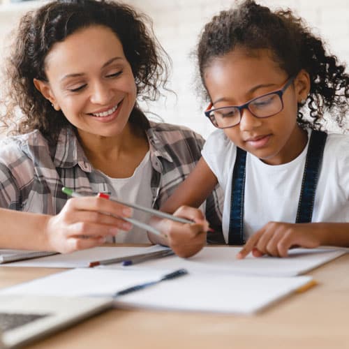 Jeune femme aidant une petite fille à faire ses devoirs