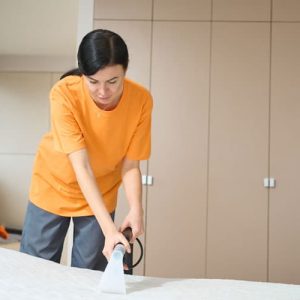 Jeune femme qui passe l'aspirateur sur du mobilier