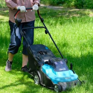 Femme qui passe la tondeuse à gazon dans un jardin