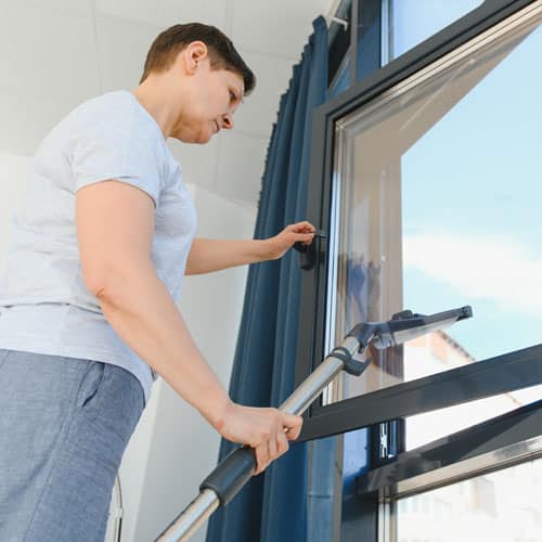 Femme qui nettoie les vitres d'une fenêtre