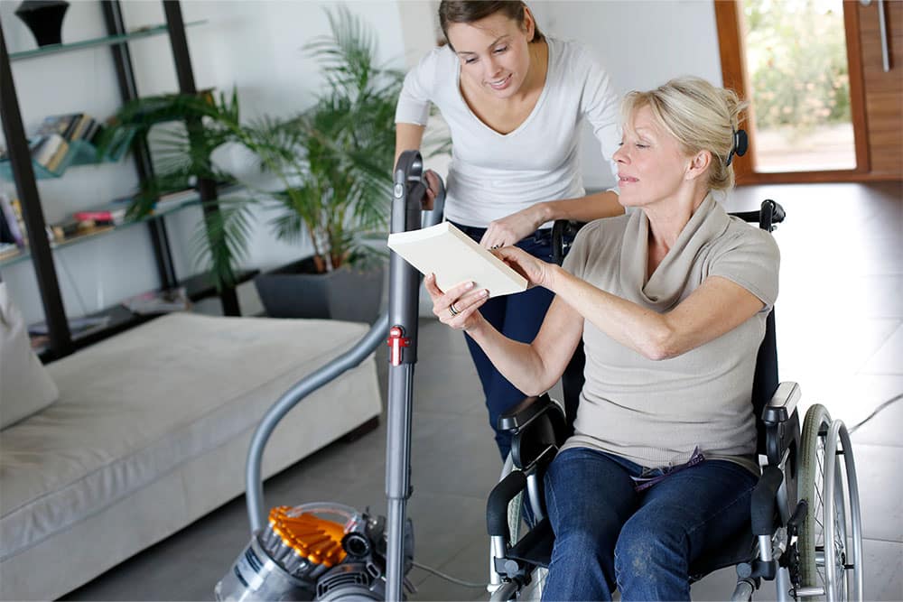 femme handicapée montrant un livre à une aide ménagère