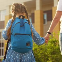 Nounou qui tient la main à une fille sur la route pour aller à l'école