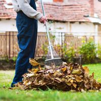 Homme en train de ramasser les feuilles mortes d'un jardin